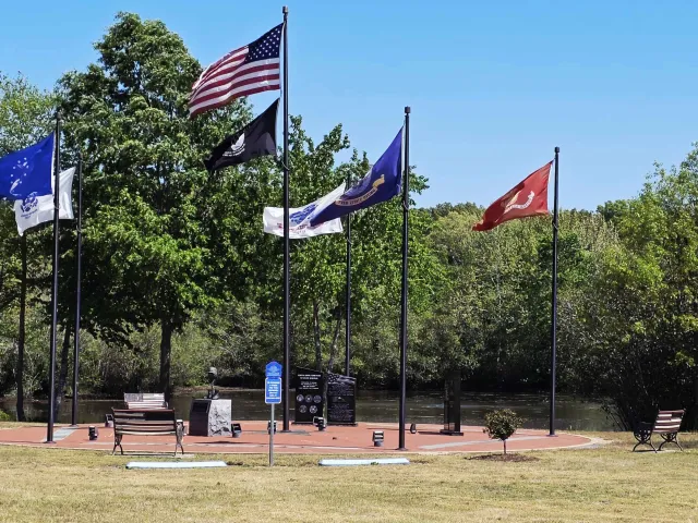 The Federalsburg Hometown Veterans Memorial with flagpoles and a black granite monument overlooking the water.